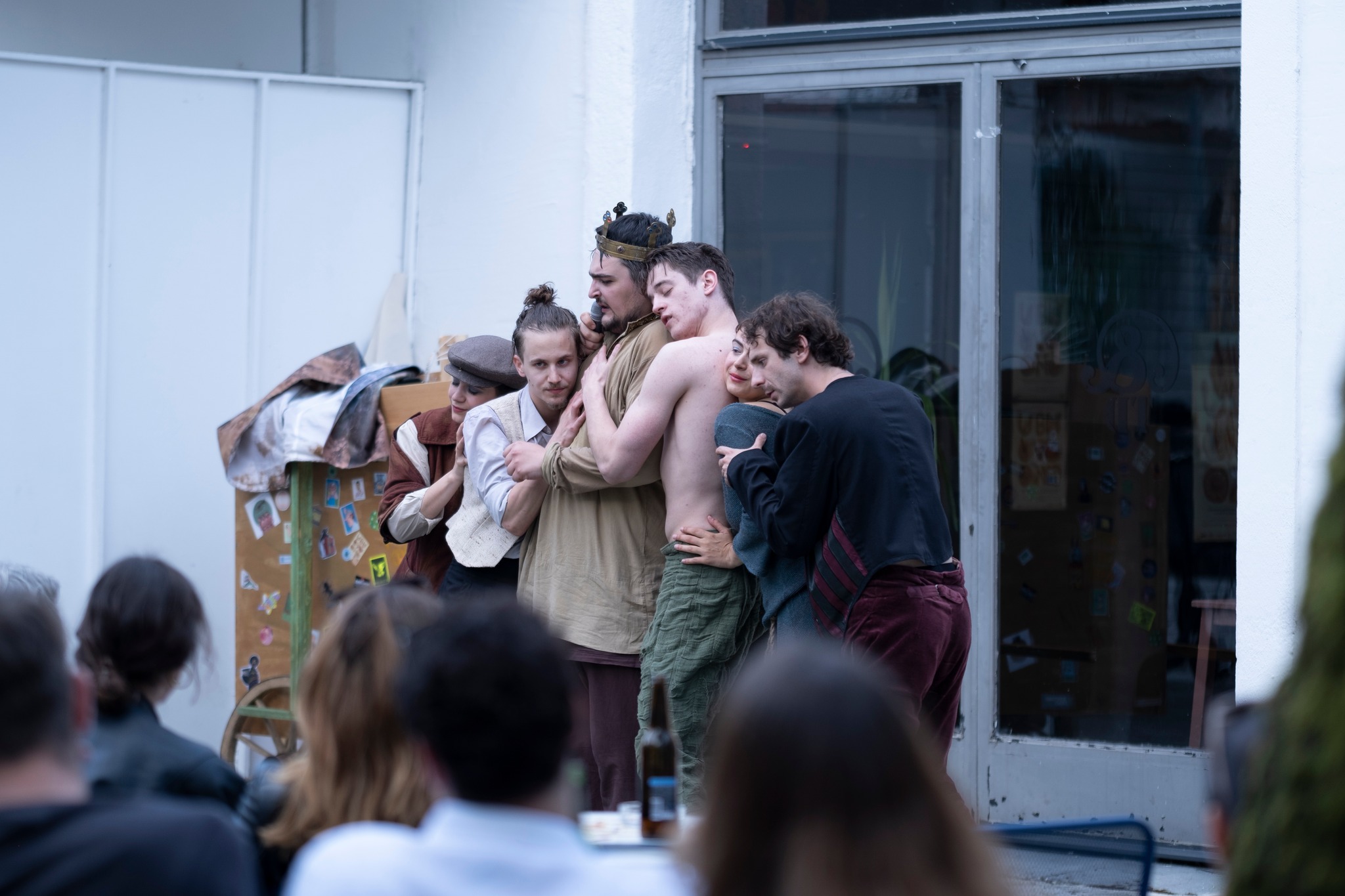 Fotografija prikazuje glumca koji igra Kralja Ubuja u sredini, okruženog glumcima i glumicama koji ga grle.