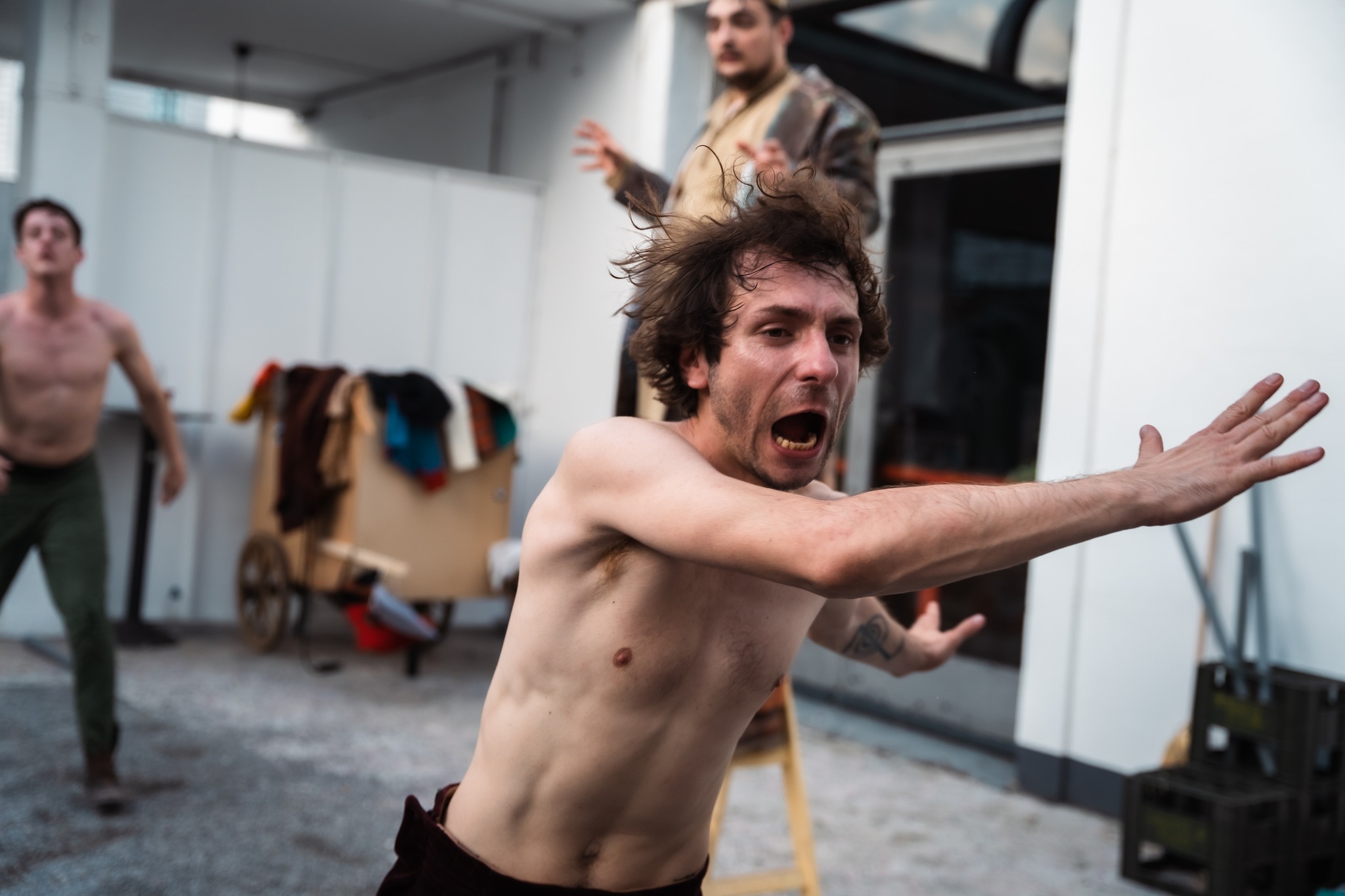 Fotografija prizora iz predstave u kojem glumac u toplesu izvodi energičnu fizičku radnju.