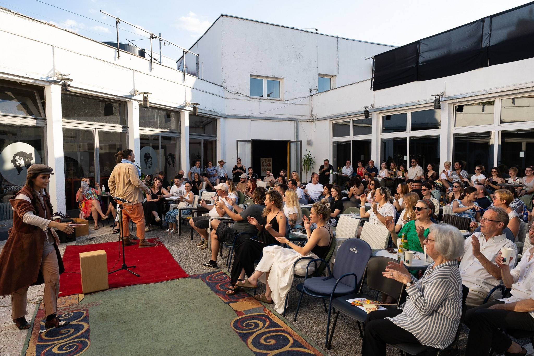 Fotografija publike koja plješće glumcima u atriju.